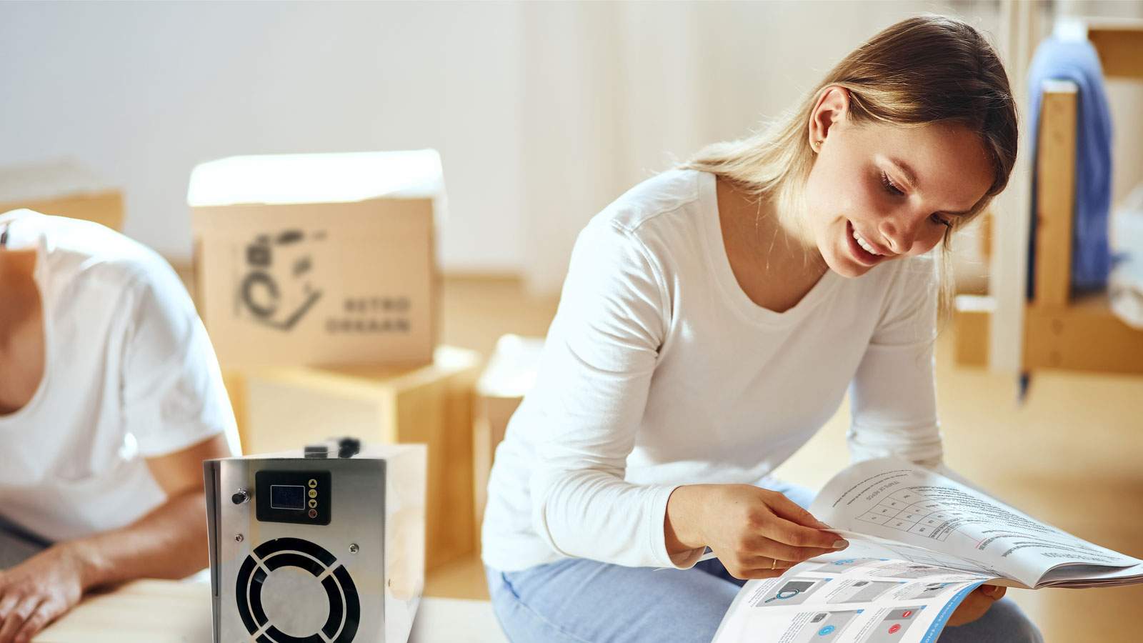 femme lit la notice d'un orkaan déballé poser a coté d'elle avec des cartons en fond