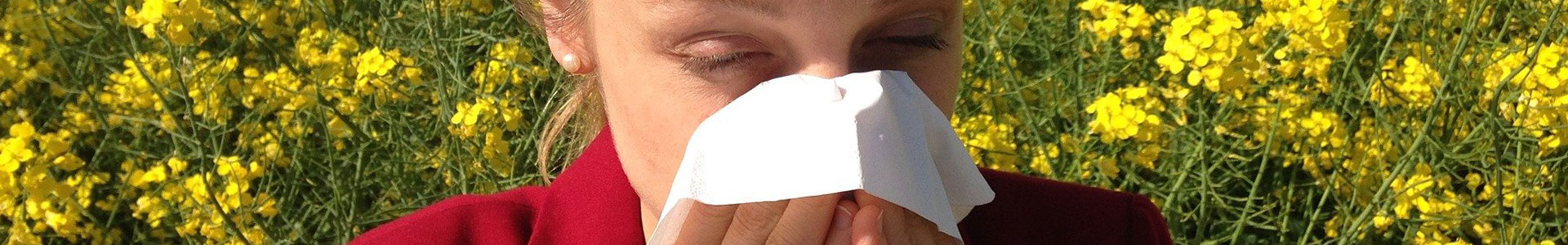 Image d'une femme entrain de se moucher car elle est entourée de plantes jaunes