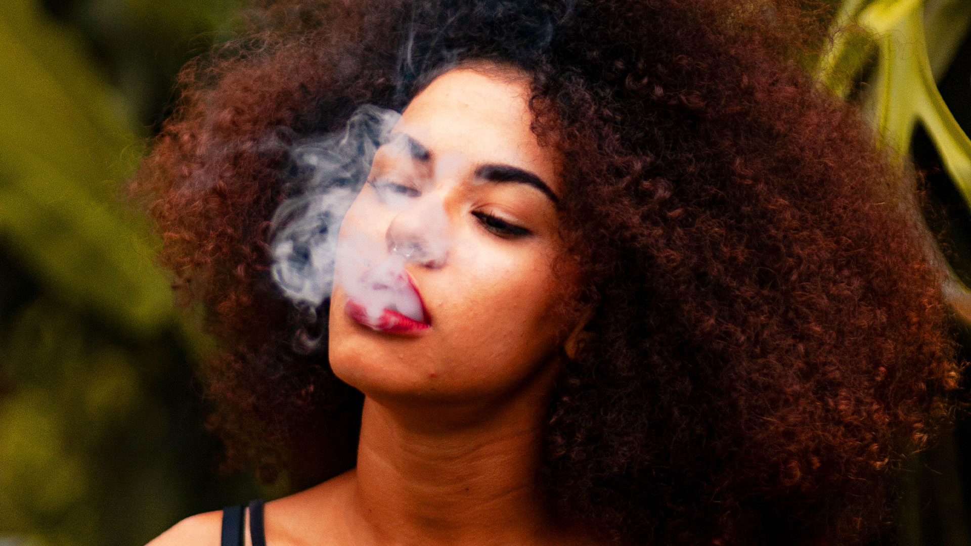 Une femme aux cheveux frisés qui fume.