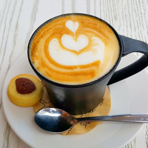 Cappuccino dans une tasse accompagné d'un biscuit et d'une cuillère à café