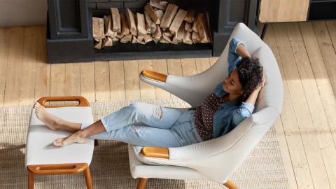 Une femme qui est assise dans son canapé et qui se détend dans un chalet.